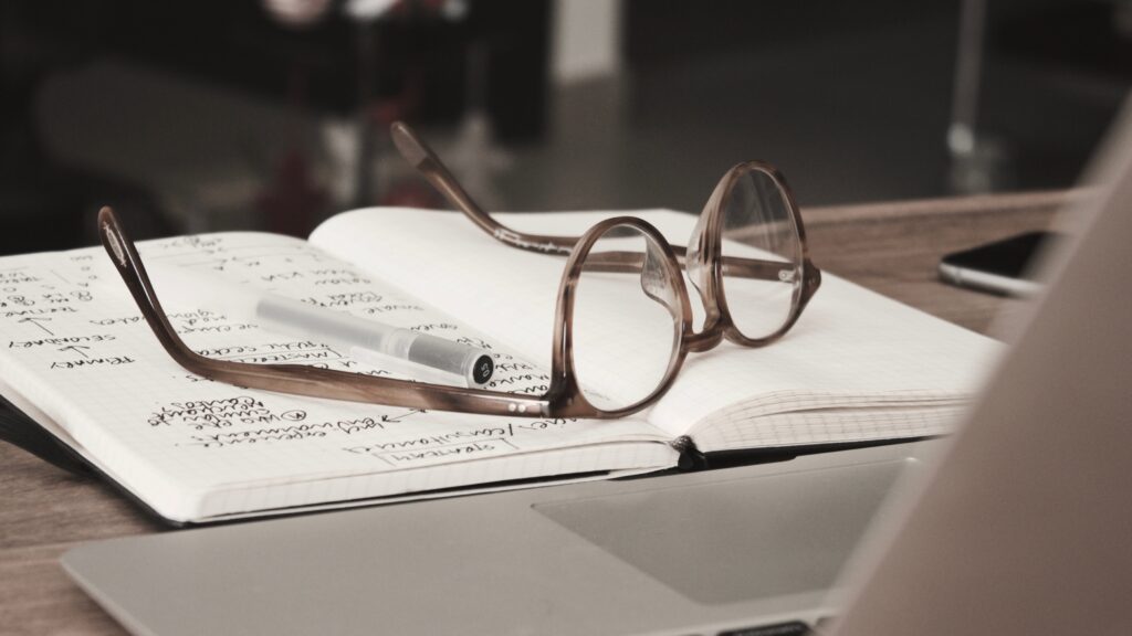 a photo of eyeglasses on top of a notebook with a lot of notes which is being used to write one's options on what to do with an abandoned mobile home