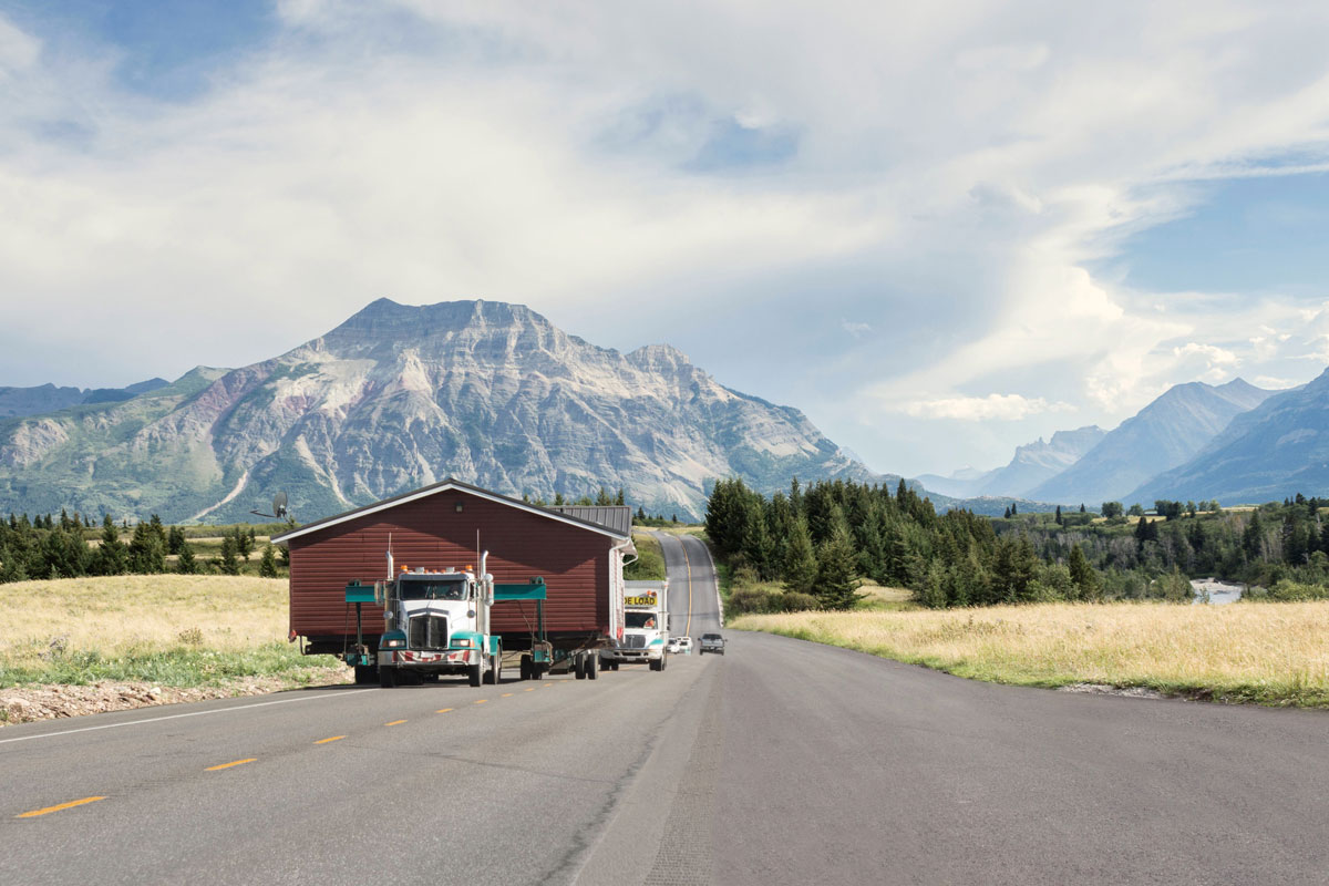 truck moving a mobile home with mountain range in background